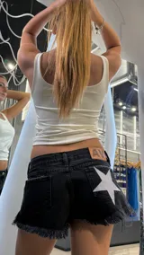 Short de jean negro de tiro bajo, con ruedo desflecado y detalle de estrella grande con glitter plateado en el bolsillo trasero derecho. Incluye etiqueta de cuero sintético en la parte posterior.