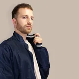 Campera bomber azul de nylon con cuello alto, cierre frontal, puños y cintura acanalados con rayas blancas y grises.