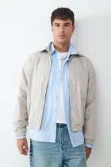 Campera de estilo casual con cuello tipo solapa, cierre frontal de cremallera y bolsillos laterales. Presenta puños y ruedo elásticos, con un acabado de textura ligera.