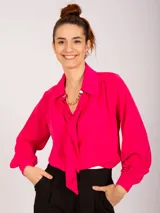 Blusa negra de manga larga con cuello camisero y lazo frontal. Presenta frunces en los hombros y puños ajustados con elástico.