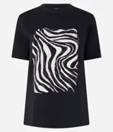 Remera de algodón color negro con cuello redondo y mangas cortas. Presenta una estampa frontal abstracta con líneas onduladas en tonos claros.