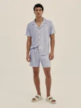 Camisa de hombre de manga corta, color azul marino, con cuello tipo camp-collar y botones de madera. La tela es tipo toalla.