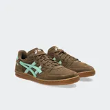 Championes Asics modelo Skyhand OG, de diseño retro inspirado en el balonmano de los años 90. Confeccionados en gamuza color marrón con detalles en verde menta en los laterales y el talón, cuentan con suela de goma color caramelo y amortiguación de EVA en el talón.