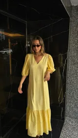 Vestido largo color amarillo pálido, con escote en V, mangas cortas abullonadas con detalle de calado y ruedo con volantes y calado.