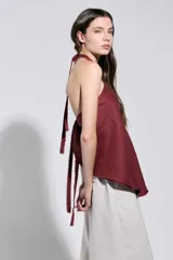 Top bordó con cuello halter cruzado y bordes deshilachados, de corte acampanado y caída suave.