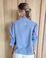 Blusa de algodón con cuello mao y volados, mangas largas con puños elásticos y corte holgado.