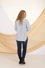 Camisa verde militar de corte holgado, con cuello clásico, cierre frontal con botones, bolsillo de parche en el pecho y mangas largas con puños abotonados.