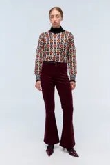 Pantalón de pana color bordó, corte oxford, con cintura alta y cierre frontal con botón y cremallera.