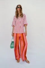 Camisa de corte oversize con estampado de rayas verticales rojas y blancas. Presenta cuello solapa, escote en pico y mangas largas abullonadas con puños elásticos.