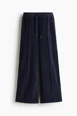 Pantalón tipo jogger de corte amplio confeccionado en tejido de velour suave. Presenta cintura elástica con cordón de ajuste y detalle de pliegue cosido vertical en el frente de cada pierna.