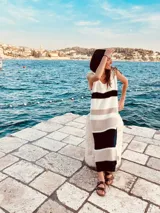 Vestido largo tejido a rayas horizontales en tonos blanco, beige y negro, de corte recto y sin mangas.