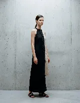 Vestido largo de lino con diseño asimétrico en combinación de colores negro y beige, con detalle de galón central en encaje. Presenta cuello halter y corte recto.