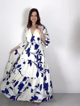 Vestido largo de viscosa con estampado floral en tonos azules sobre base blanca, escote en V cruzado, mangas tres cuartos y falda escalonada con volados.