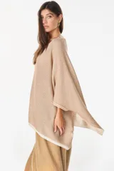 Blusa de punto tipo poncho en color beige, con diseño amplio y reversible, escote redondo y detalles de ribete en el borde inferior.