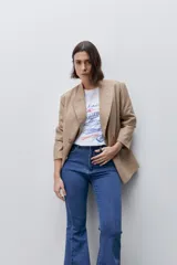 Jean flare de tiro alto, color azul, con calce ajustado en cadera y muslos, y ruedo desflecado.