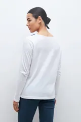 Remera blanca de manga larga con bordado floral azul en el escote.