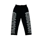 Pantalón negro de algodón con diseño estampado en los laterales que simula letras con efecto de brillantes o pedrería. Posee cintura elástica y corte recto.