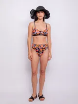 Conjunto de bikini con corpiño triangular con breteles finos y bombacha de tiro alto. Estampado multicolor con motivos florales y geométricos.