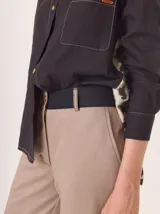 Pantalón de vestir azul marino, corte cigarette con pierna angosta y abertura en el bajo. Presenta costuras en contraste color beige y un botón marrón en la cintura.