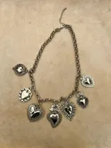 Collar de cadena de eslabones plateados con múltiples dijes colgantes en forma de corazones con diversos relieves y diseños de estilo vintage.
