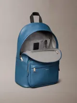 Mochila Calvin Klein de poliuretano texturizado en color azul, con compartimento principal con cierre de doble cremallera, bolsillo frontal con cierre, asa superior y tirantes ajustables. Incluye detalle de logo metálico de la marca en el frente.