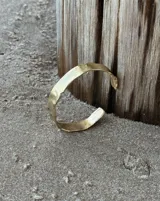 Pulsera tipo esclava abierta con diseño rústico y acabado irregular, fabricada en bronce y alpaca.