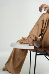 Zapatillas bajas color beige y marrón, con cordones y suela blanca.