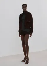 Jersey de punto gris oscuro con cuello alto y mangas largas, de diseño entallado y textura acanalada.