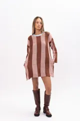 Buzo tipo poncho de corte oversize, con diseño de bloques verticales en tonos marrón y rosado. Presenta cuello redondo en color celeste, mangas largas y bolsillos laterales integrados.