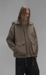 Campera técnica liviana color beige, confeccionada en microfibra de alta densidad con acabado mate. Presenta mangas desmontables que permiten convertirla en chaleco, cuello tipo camisa, cierre frontal oculto bajo cartera y logo bordado en el pecho. Incluye cuatro bolsillos frontales de gran tamaño con solapa y puños con elástico.