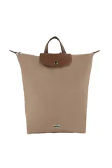 Mochila Las Oreiro de diseño minimalista en color beige, con solapa superior en cuero sintético marrón y cierre de botón a presión. Presenta un aplique metálico con forma de labios en la parte inferior y asas superiores.