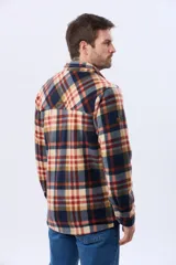 Campera polar de hombre con estampa a cuadros en tonos neutros y azules, confeccionada con tejido polar suave. Presenta cierre frontal, cuello camisero, bolsillos con solapa en el pecho y calce cómodo.