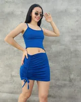 Conjunto azul eléctrico compuesto por un top corto con tirantes finos y una minifalda con frunces laterales y lazos ajustables.