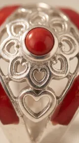 Anillo de plata 925 con diseño calado de motivos florales y corazones, decorado con esmalte rojo y una piedra central circular.