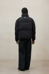 Campera acolchada negra, estilo puffer, con cuello alto y cierre frontal. Diseño oversize.