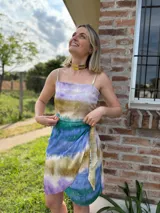 Falda corta cruzada con estampado batik en tonos verde, azul, marrón y lila, con detalles dorados y lazo lateral.