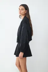 Campera bomber de textura satinada con cierre frontal de cremallera, cuello redondo y mangas largas con puños elásticos.