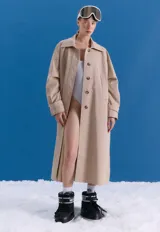 Trench midi color camel, confeccionado en mezcla de algodón y nylon. Presenta cuello clásico, cierre frontal con botones, tajos laterales y bolsillos internos. Es una prenda repelente al agua con diseño versátil y funcional.