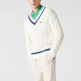 Sweater de tejido de punto trenzado color crema, con cuello en V y rayas azul marino y celeste. Logo de la marca bordado en el pecho.