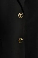 Blazer entallada de color negro con cuello solapa, manga larga y hombreras marcadas. Presenta cierre frontal con dos botones dorados y bolsillos delanteros con solapa.
