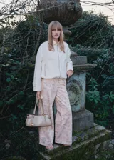 Pantalón jeans de corte wide leg y tiro alto, confeccionado en algodón con estampado floral en tonos suaves. Presenta diseño de cinco bolsillos, cierre frontal con cremallera y botón, y trabillas en la cintura.