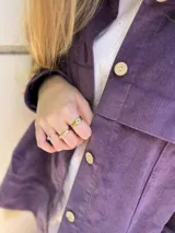 Campera corta de pana color violeta con cuello camisero, cierre frontal con botones dorados, bolsillos de parche en el pecho y corte recto.