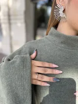 Polerón de cuello alto en color verde oliva, con diseño de calce holgado y mangas amplias. Confeccionado en tejido de punto suave y abrigado.