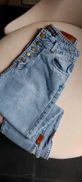 Pantalón de jean celeste de corte recto, con bolsillos delanteros y traseros, y etiqueta de cuero marrón en la parte posterior de la cintura.