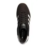 Championes Adidas Gazelle Indoor, modelo de corte clásico y retro fabricado en gamuza de color marrón oscuro, con las tres franjas características de la marca y la lengüeta del talón en color blanco. Incluye la inscripción "GAZELLE" en letras doradas en el lateral y suela de caucho translúcido tipo caramelo.