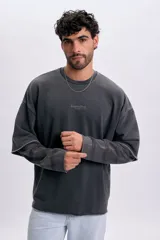 Sudadera gris oscuro de doble manga con efecto desgastado, cuello redondo y bordado frontal pequeño con texto.
