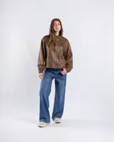 Campera cropped tipo bomber color marrón con acabado vintage, capucha con cordón ajustable, cierre frontal y puños y ruedo elásticos.