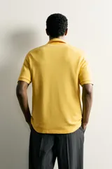 Sudadera polo regular fit de manga corta color mostaza, confeccionada en tejido con mezcla de algodón e interior de rizo, con cuello solapa y cierre frontal de botonadura.