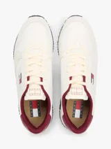 Zapatillas runner Tommy Jeans Eva de estilo urbano, confeccionadas en una combinación de cuero blanco, textil y material sintético. Presentan detalles en color bordó en el talón y el interior, entresuela con franja marrón y suela dentada azul. Cuentan con el logo de Tommy Jeans bordado en el lateral.