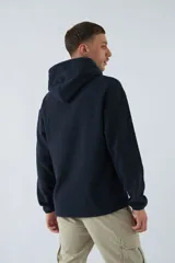 Buzo canguro color marrón de polar con capucha, bolsillo tipo canguro y logo estampado en el pecho.